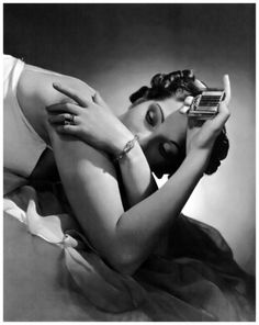 a woman laying on top of a bed holding a cell phone