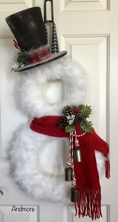 a snowman wreath with a top hat and scarf hanging on the front door handle