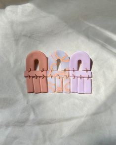 four pieces of pastel colored hair clips on a white sheet with gold and pink designs