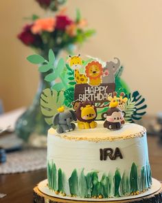 a birthday cake with animals on it sitting on top of a wooden table next to flowers