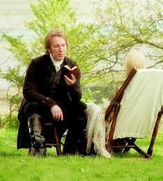 a man sitting in a chair next to a woman on the grass near a tree