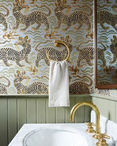 a white sink sitting under a mirror next to a gold faucet