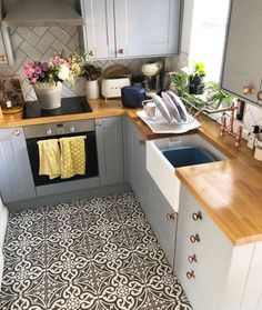 a kitchen with grey cabinets and wooden counter tops is pictured in this image, there are yellow towels hanging on the sink