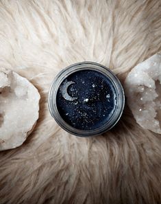 a jar filled with blue liquid sitting on top of a fur covered floor next to an object