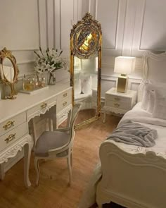 a bedroom with white furniture and gold accents on the mirror, dressers and bed