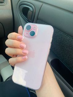 a woman is holding up her phone in the back seat of a car with pink nail polish on it