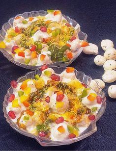 two bowls filled with food sitting on top of a blue cloth covered table next to small white teddy bears