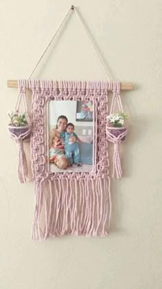 a pink frame hanging on the wall with a photo and flowers in it, attached to a wooden stick