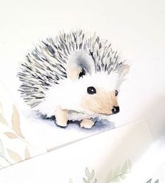 a watercolor painting of a hedgehog sitting on top of a piece of paper