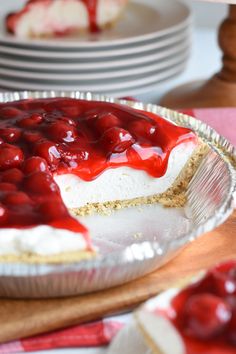 a pie with cherries on it sitting on a wooden cutting board next to plates