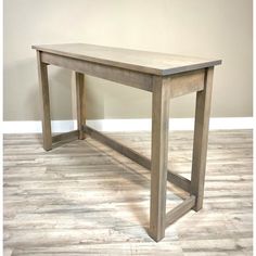 a wooden table sitting on top of a hard wood floor next to a white wall