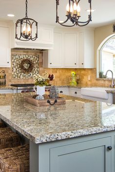 a large kitchen with marble counter tops and white cabinets