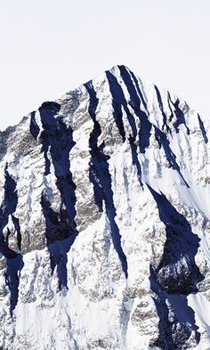 a large mountain covered in snow under a blue sky with a plane flying over it