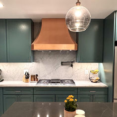 a kitchen with green cabinets and marble counter tops, an island in the middle has yellow flowers on it