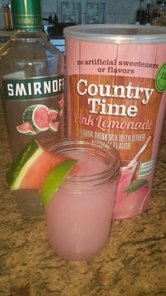 a pink drink next to a can of country time watermelon on a counter