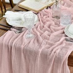 the table is set with pink linens and silverware