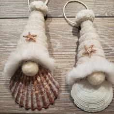 two seashells with santa hats and starfish on them are sitting on a wooden surface