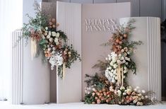 an arrangement of flowers and greenery on display in front of a white wall with the words apapan panasa