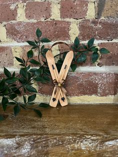 pair of wooden scissors on wood table next to brick wall