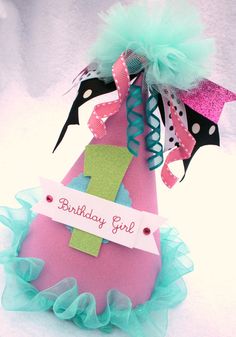 a pink birthday hat with a green bow and number one on it's side