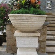 a large planter sitting on top of a stone pillar in front of some steps