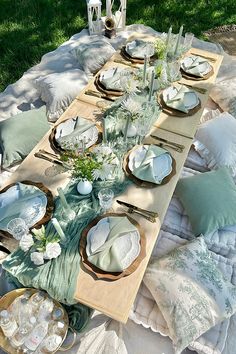 an outdoor table set with plates and place settings