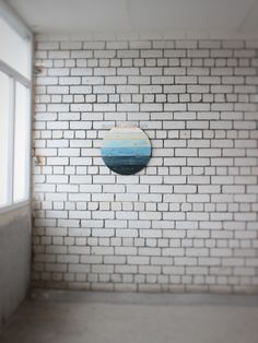 a white brick wall with a round painting on it