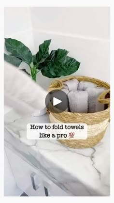 a basket filled with towels sitting on top of a counter next to a potted plant