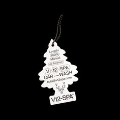 a white christmas tree shaped tag hanging from a black background with the words spa and car wash written on it