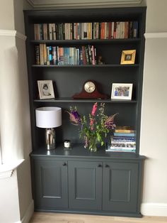 a bookshelf filled with lots of books next to a lamp and pictures on the wall