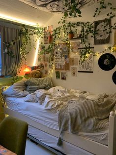 an unmade bed with lots of plants growing on the wall and hanging from the ceiling