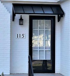 the front door of a white house with black shutters and a number on it