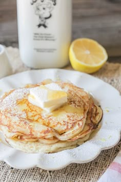 a stack of pancakes with butter and syrup on a plate next to a bottle of milk