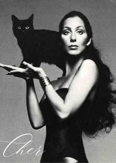 a woman holding a black cat in her hands