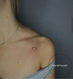 a woman's chest with a small heart tattoo on the left side of her shoulder