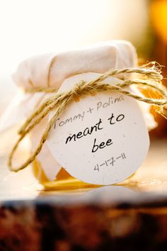 a jar filled with honey sitting on top of a wooden table next to a white tag