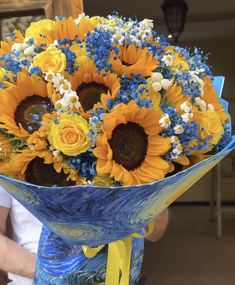 a bouquet of sunflowers in a blue vase with yellow ribbon tied around it