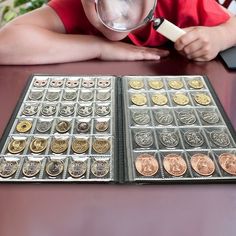 a young boy looking through a magnifying glass at some gold and silver coins