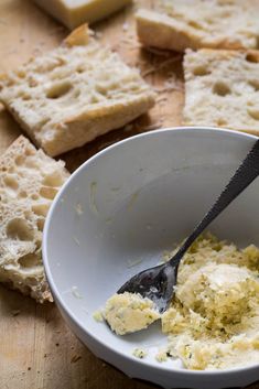 a white bowl filled with food next to slices of bread