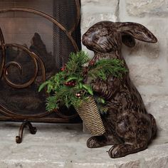 a rabbit sitting next to a fireplace with a basket full of christmas greenery in front of it