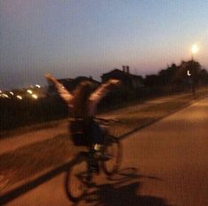 a person riding a bike with their arms in the air on a street at night