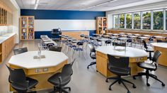 an empty classroom with desks and chairs in front of the windows, along with bookshelves