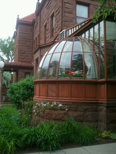 an old brick building with many windows and plants