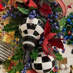 a christmas tree is decorated with black and white balls, red bows, and holly