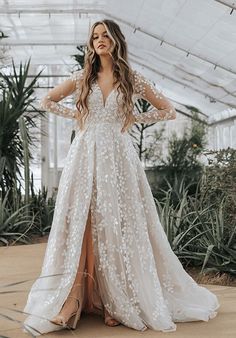 a woman in a white wedding dress with long sleeves and an open back standing on a patio