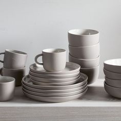 a stack of white cups and saucers sitting on top of a table