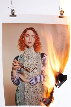 a woman with red hair holding a cell phone in front of a burning photo frame