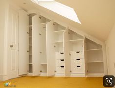 an empty room with white closets and yellow carpeting on the floor in front of a slanted ceiling