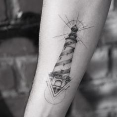 a black and white photo of a lighthouse tattoo on the right forearm, with an arrow in the middle