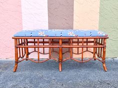 a wooden bench with a blue cushion on it in front of a multi - colored wall